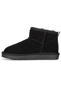 Botas cortas negras de ante con un suave forro de piel. Cuentan con una suela de goma plana con bordes dentados y una lengüeta en la parte trasera.