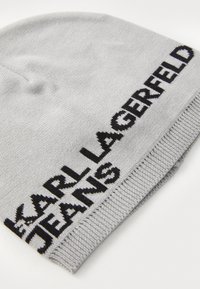 Gray knit beanie featuring "KARL LAGERFELD" and "JEANS" in black embroidery, with a smooth texture and a snug fit.