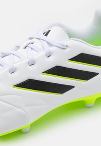 Bota de fútbol blanca con franjas negras y acentos en verde neón. Presenta un upper de cuero liso y un detalle texturizado en las franjas.