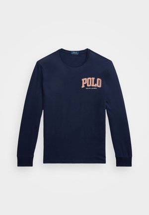 Marineblå langermet skjorte laget av bomull. Har rund hals og en fremtredende "POLO"-logo i oransje på venstre bryst.