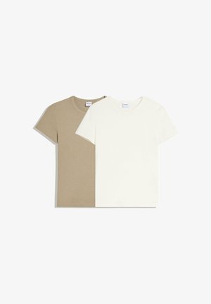 Dvě jednoduchá trička s krátkými rukávy a kulatým výstřihem, jedno béžové a jedno bílé, pečlivě naskládaná na bílém pozadí.