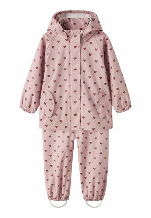 Rosa Kinder-Regenanzug mit braunem Herzmuster, Kapuzenjacke mit Knöpfen vorne, zwei Taschen und elastischen Bündchen an der Hose mit Fußriemen.