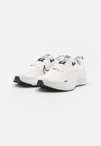 Baskets de course blanches avec une tige en mesh respirant, des accents noirs sur la semelle et une semelle intermédiaire rembourrée. Elles sont dotées de lacets et d'un détail de logo.