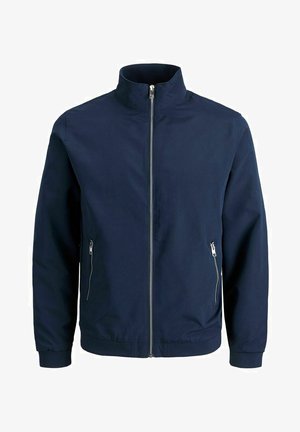 Chaqueta bomber de color azul marino con un cuello alto, cierre frontal con cremallera y dos bolsillos laterales con cremallera. Fabricada con una tela ligera y suave.