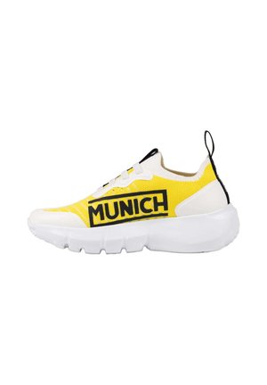 Sneaker gialla e bianca con suola spessa bianca, linguetta nera sul tallone e la parola "MUNICH" stampata in nero sul lato.