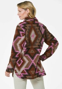 Veste en polaire marron, rose et grise avec des motifs géométriques. Dotée d'un col, de manches longues et de poignets à boutons. Matériau texturé et chaud.