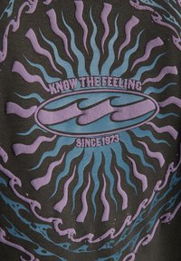 Rayos ondulados púrpuras y azules alrededor de un óvalo con olas estilizadas y el texto "Conoce la sensación desde 1973" sobre un fondo de tela oscura.