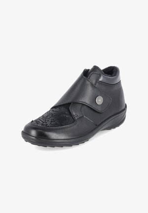 Schwarzer Lederknöchelschuh mit verstellbarem Riemen, strukturiertem Vorderteil, weichem Futter und flacher, niedriger Sohle für komfortables Gehen.