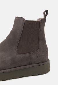 Grå mocka Chelsea boot med elastiska sidopaneler, strukturerat tyg och en kontrasterande mörk sula. Har upphöjd logotyp på hälen.