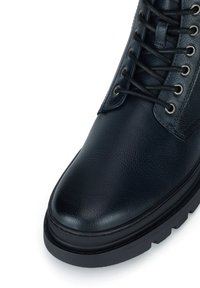 Černá kožená bota s kulatou špičkou, texturovaným povrchem, kovovými očky a černými tkaničkami. Obsahuje silnou, robustní podrážku pro zvýšenou odolnost.