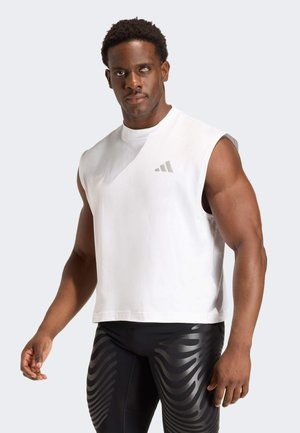 Top deportivo blanco sin mangas con escote redondo y un logotipo gris. Combinado con mallas negras que presentan un diseño de patrón ondulado.