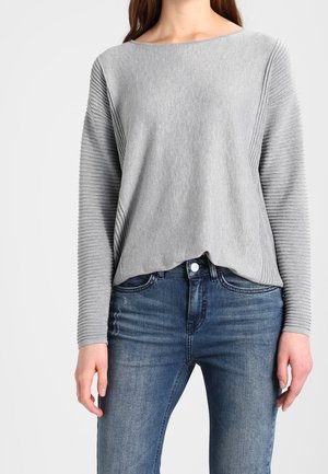 Graues Langarmoberteil mit gerippter Textur an den Seiten, runder Ausschnitt und lockere Passform, kombiniert mit blauen Jeans.