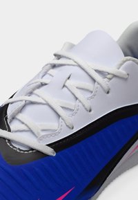 Μπλε και μαύρο αθλητικό παπούτσι με λευκά κορδόνια, με λείο επάνω μέρος, υφασμένες πλαϊνές επιφάνειες και ροζ λογότυπο swoosh ως ένδειξη.