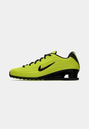 Neon geltonos ir juodos spalvos Nike sportbačiai su juodu swoosh, su raišteliais užsegama konstrukcija ir suformuota padas ant balto fono.