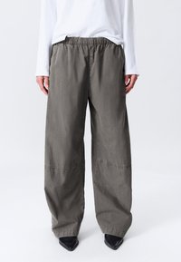 Pantalon gris à jambes larges avec une ceinture élastique, confectionné dans un tissu doux et texturé. Présente des détails cousus et une silhouette décontractée.