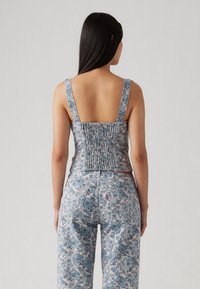 Blommönstrad jeansskjorta med breda band, smockad bakdel och ljusblå nyanser, i kombination med matchande blommiga jeans med en lös passform.