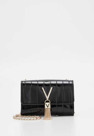 Zwarte lakleren clutch met verticale stiksels, gouden kettingriem, gouden "V"-sluiting en kwastdetail op een witte achtergrond.
