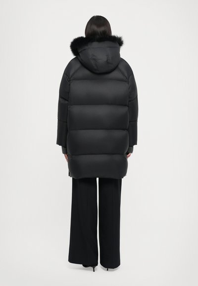Black padded puffer coat with a hood and faux fur trim. Features a quilted design, slightly oversized fit, and wide sleeves.