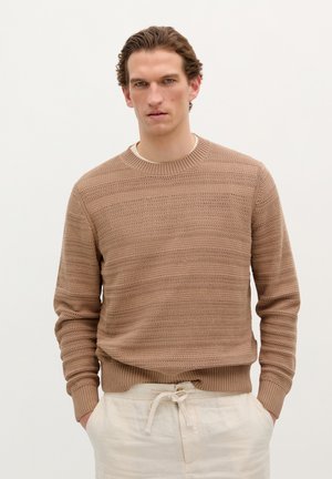 Suéter de punto en beige claro con rayas horizontales texturizadas y puños acanalados. Combinado con pantalones de tiro alto de color crema con cordón.