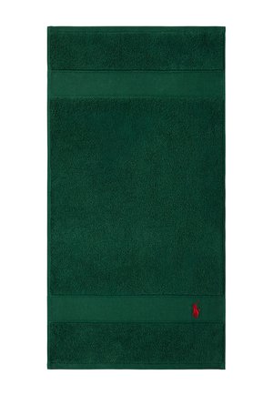 Asciugamano rettangolare verde scuro con bordi sagomati e un piccolo logo rosso ricamato nell'angolo in basso a destra.