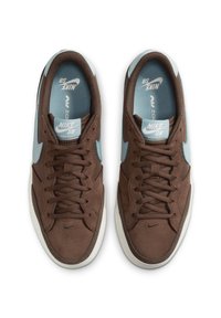 Brune sneakers med lyseblå accenter, tekstureret stof, flade snører og en hvid sål. Logo vist på tungen og siden.