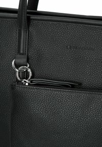 Sac fourre-tout noir en matériau texturé cuir, avec des accessoires en métal argenté et une poche zippée à l'avant. Logo gaufré sur la surface.