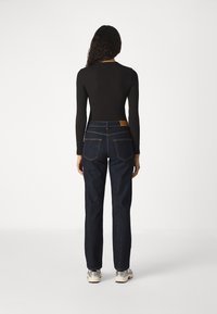 Černý dlouhý rukáv, modré široké džíny s vysokým pasem, dvě zadní kapsy a béžová kožená nášivka na pase. Stříbrné tenisky.