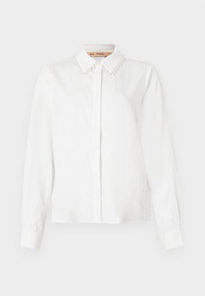 Blusa branca de manga longa com colarinho decorado com pérolas, botões frontais ocultos e punhos ajustados, em fundo liso.