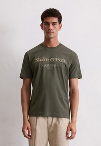 Olijfgroene katoenen T-shirt met ronde hals. De voorkant heeft bedrukte tekst in lichtbruin, met een iets ontspannen pasvorm en korte mouwen.