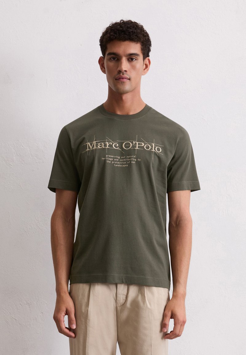 Olijfgroene katoenen T-shirt met ronde hals. De voorkant heeft bedrukte tekst in lichtbruin, met een iets ontspannen pasvorm en korte mouwen.