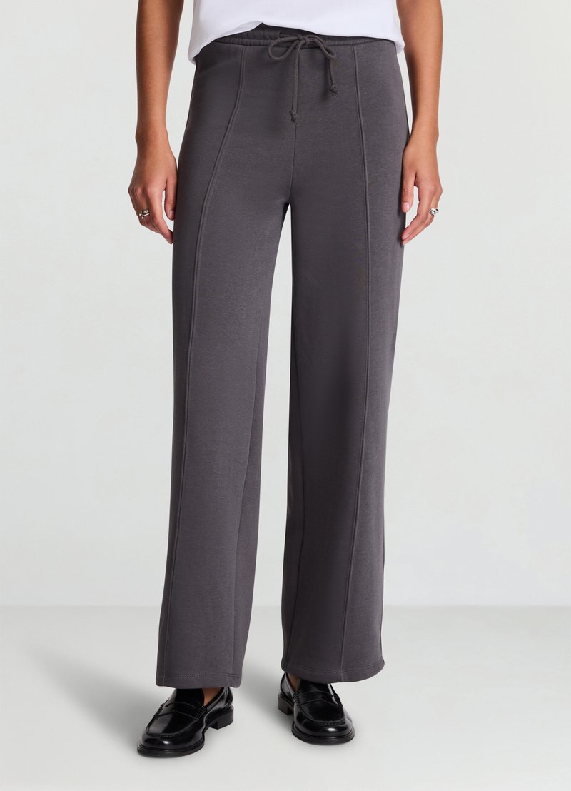 Pantaloni grigi a gamba larga in tessuto morbido con cintura regolabile a coulisse, caratterizzati da dettagli di cucitura visibili e vestibilità confortevole.