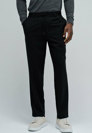Pantalones jogger negros hechos de tela suave, con cintura elástica con cordón, bolsillos laterales y diseño de pierna recta.