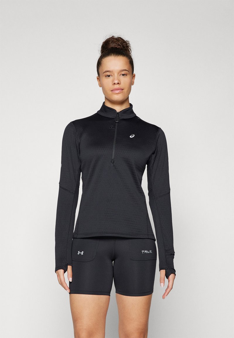 Maglia sportiva nera a maniche lunghe con collo zip e tessuto strutturato, abbinata a pantaloni corti sportivi neri con tasche laterali e marchio.