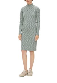 Długo rękawowa, obcisła sukienka z teksturowanej zielonej dzianiny, z wysokim kołnierzem i długością do kolan, w połączeniu z jasnymi trampkami.