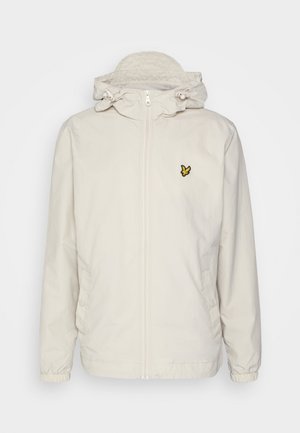 Giacca zip-up beige chiaro con cappuccio, polsini elastici e tasche laterali. Presenta un piccolo logo ricamato nero e giallo sul petto.