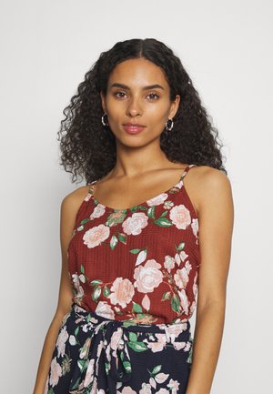 Camisola de flores castanha com alças finas, apresentando padrões florais em rosa e verde, tecido texturizado, combinada com uma saia escura de flores.