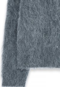 Suéter gris de felpa con un acabado suave y texturizado. El material parece de lana y presenta un diseño de punto suelto con una silueta ligeramente oversized.