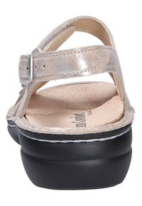 Vue arrière d'une sandale en cuir beige à finition métallique, avec bride de cheville ajustable, semelle intérieure rembourrée et semelle épaisse noire.