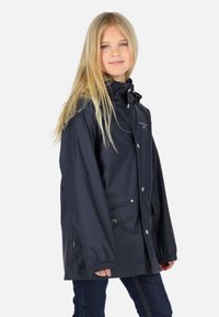 Giacca impermeabile blu navy con collo alto, bottoni a pressione, due tasche frontali, polsini elasticizzati e logo sul petto. Tessuto resistente e dalla consistenza liscia.