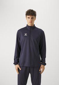 Marinefarbener, Reißverschluss-Sportpullover mit langen Ärmeln, aus glattem, dehnbarem Material gefertigt. Verfügt über ein kleines weißes Logo auf der Brust.