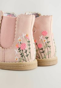 Botine roz din suede cu broderii florale în diverse culori, margini zimțate și talpă din cauciuc texturat.