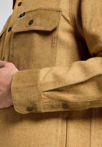 Bruine corduroy shirt met gestructureerde strepen, voorzien van twee borstzakken, knoopsluitingen en geëtiketteerde hardware accenten.