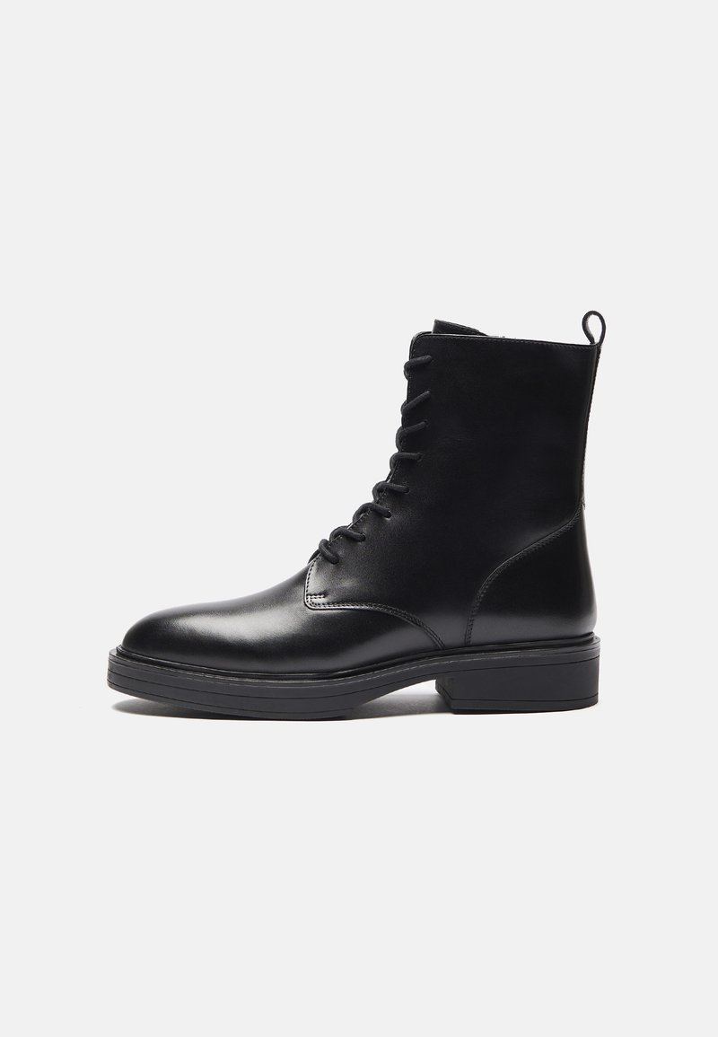 Bota negra de cuero hasta el tobillo con punta redonda, frente con cordones, tira de agarre y suela texturizada. Acabado suave y diseño minimalista.
