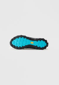 Semelle de chaussure en caoutchouc noire dotée d'une couche Vibram bleue texturée avec des crampons proéminents pour une adhérence améliorée.