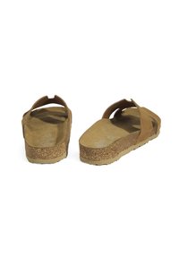 Sandales en suède marron avec une semelle en liège, dotées d'une sangle arrière, d'un design plat et d'une semelle intérieure texturée pour le confort.