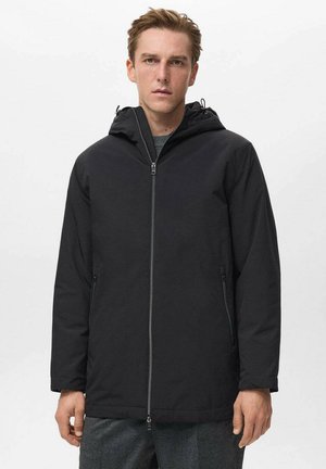 Chaqueta negra con capucha que presenta un cierre frontal con cremallera, dos bolsillos laterales y una textura suave, diseñada para un aspecto moderno.