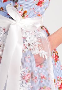 Robe fleurie avec un motif vichy bleu, une superposition en dentelle blanche et une ceinture en ruban de satin. Comprend une broderie décorative et une poche latérale.