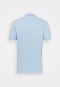 Polo bleu clair à manches courtes avec col, vu de dos sur un fond blanc uni.