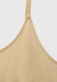 Camisola in cotone beige con spalline sottili, una texture liscia e un design aderente con cuciture precise lungo il collo e le cuciture.