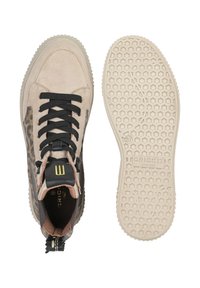 Sneakers mają beżowy zamsz i wzór w panterkę, czarne sznurowadła, wyściełany język oraz teksturowaną, lekko kremową gumową podeszwę z heksagonalnym wzorem.